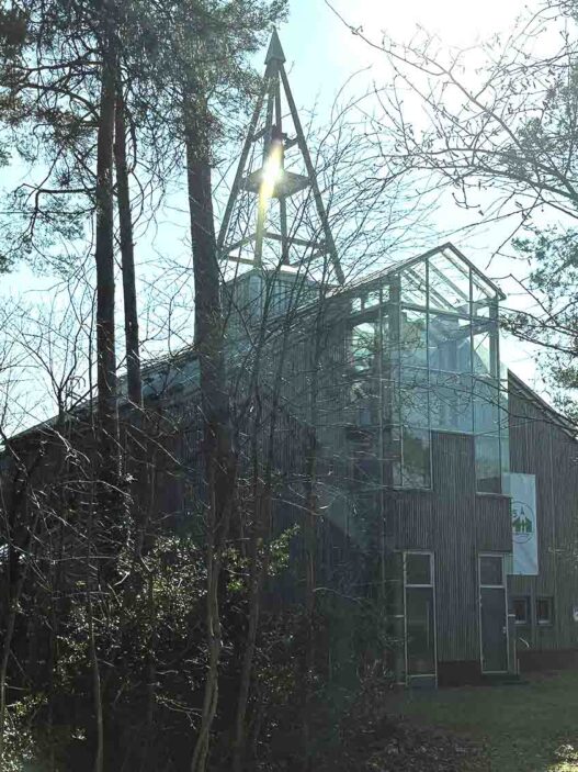 „Die Eine-Welt-Kirche in Schneverdingen – Ein beeindruckendes Beispiel nachhaltiger Architektur, erbaut aus heimischem Holz in der traditionellen Brettstapeltechnik. Die Kirche fügt sich harmonisch in die Landschaft ein und symbolisiert die Verbindung von Natur, Glaube und globaler Gemeinschaft.
